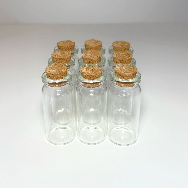 Peut inclure: Douze bouteilles en verre transparent avec des bouchons en li&egrave;ge. Les bouteilles sont dispos&eacute;es en quatre rang&eacute;es de trois bouteilles chacune.