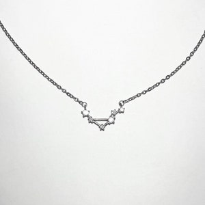 May include: A silver necklace with a constellation pendant featuring small, clear stones.