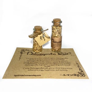 May include: Two small glass bottles with cork stoppers filled with dried herbs. The bottles are labeled "Ashwagandha Root". The bottles are sitting on a brown paper card with text about the benefits of Ashwagandha Root.