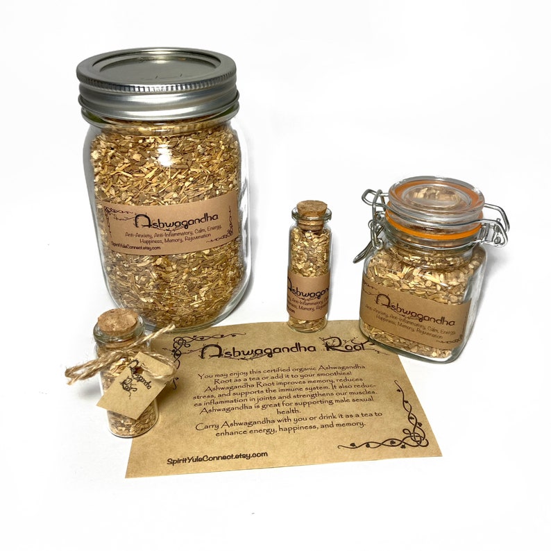 May include: Three glass jars of varying sizes filled with dried ashwagandha root. The jars have cork or metal lids. A brown paper card with the text "Ashwagandha Root" and information about the benefits of ashwagandha is in the foreground.