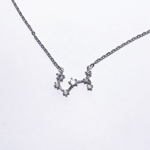 May include: A silver necklace with a constellation pendant featuring small clear stones.