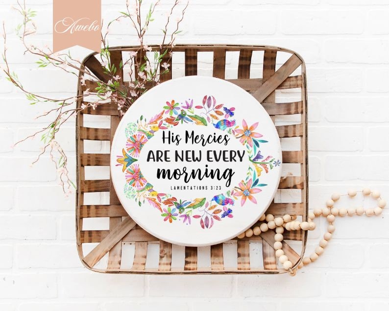May include: A round wooden sign with a watercolor floral wreath and the text "His Mercies Are New Every Morning" with the scripture reference "Lamentations 3:23".