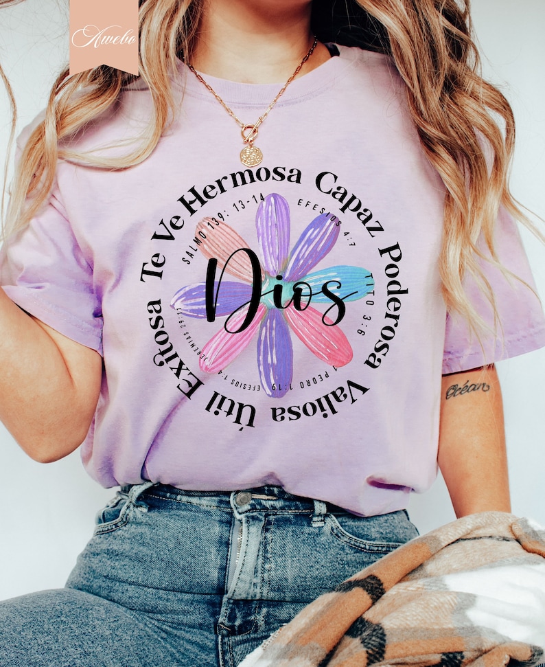 Puede incluir: Una camiseta morada con un dise&ntilde;o floral y el texto "Te Ve Hermosa Capaz Dios Poderosa Valiosa Util Exitosa" con vers&iacute;culos b&iacute;blicos alrededor del texto.