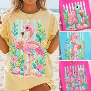 Puede incluir: Camiseta amarilla con un diseño de flamenco rosa bebiendo una bebida, rodeado de flores, hojas y conchas marinas. El diseño incluye rayas verticales azules. Otras camisetas muestran una tortuga, un caballito de mar y una langosta.