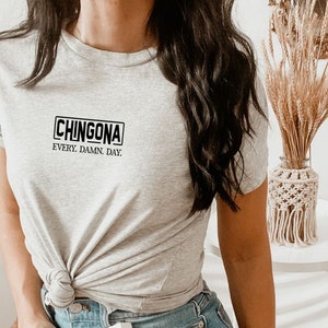 May include: A gray t-shirt with a black rectangle that says "CHINGONA" and the text "EVERY. DAMN. DAY."