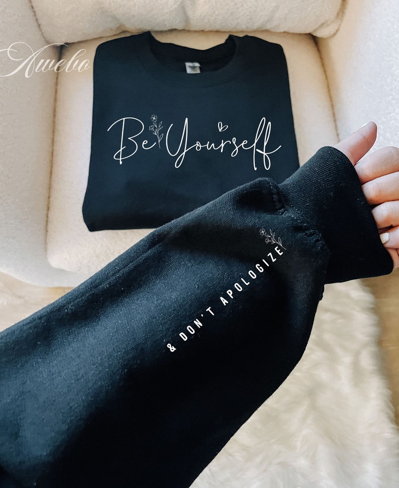 May include: Black sweatshirt with the text "Be Yourself & Don't Apologize" in white lettering. The sweatshirt has a floral design.