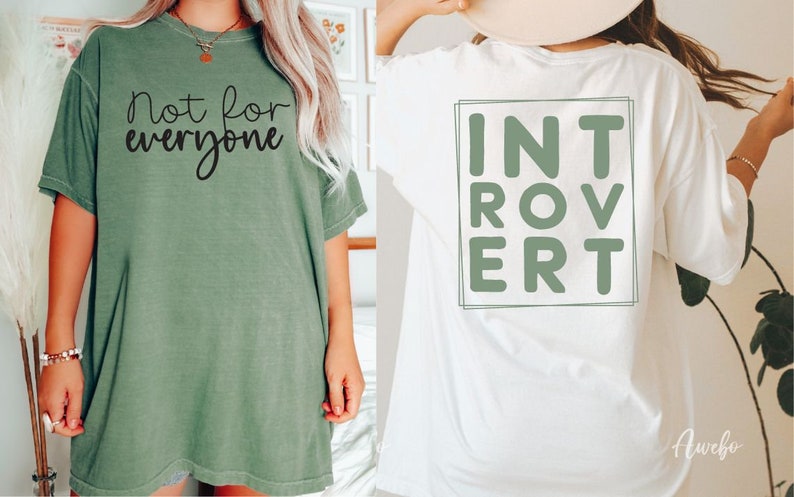 May include: Two t-shirts with different designs. The green t-shirt has the text "not for everyone" printed on the front. The white t-shirt has the word "INTROVERT" printed on the back in a green box.