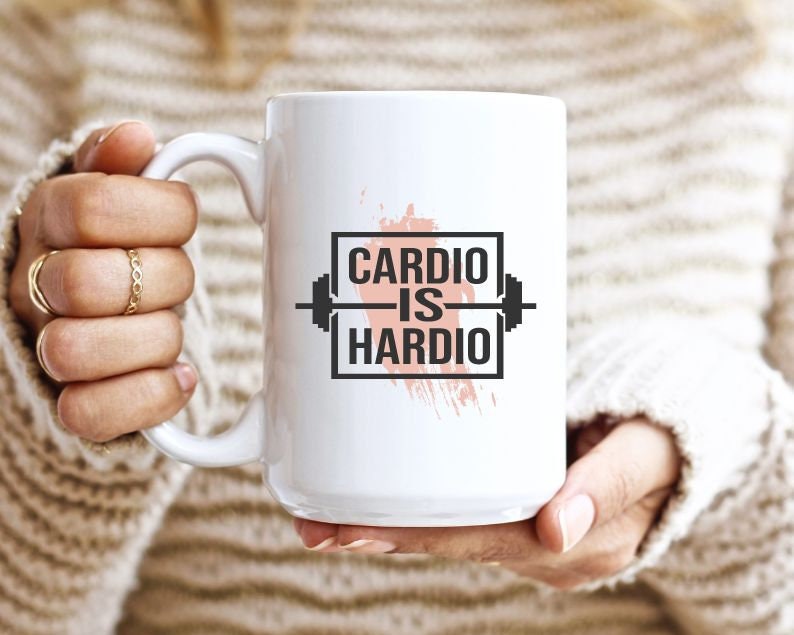 Pode incluir: Caneca de cer&acirc;mica branca com um gr&aacute;fico preto e branco que diz "Cardio is Hardio" com um gr&aacute;fico de barra. O gr&aacute;fico est&aacute; sobre um fundo de aquarela rosa.