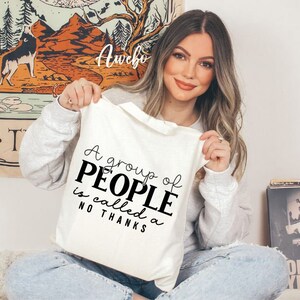 May include: A white tote bag with black text that reads "A group of PEOPLE is called a NO THANKS".