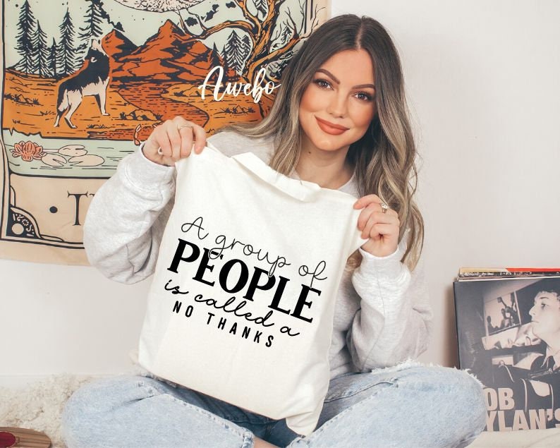 May include: A white tote bag with black text that reads "A group of PEOPLE is called a NO THANKS".