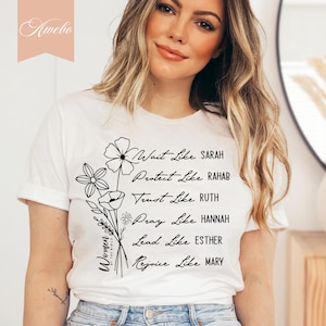 May include: White t-shirt with black text and floral designs. The text reads "Women of the Bible" and lists biblical figures with the phrase "Wait Like", "Protect Like", "Trust Like", "Pray Like", "Lead Like", and "Rejoice Like".