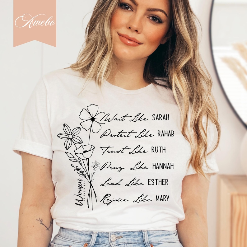 May include: White t-shirt with black text and floral designs. The text reads "Women of the Bible" and lists biblical figures with the phrase "Wait Like", "Protect Like", "Trust Like", "Pray Like", "Lead Like", and "Rejoice Like".