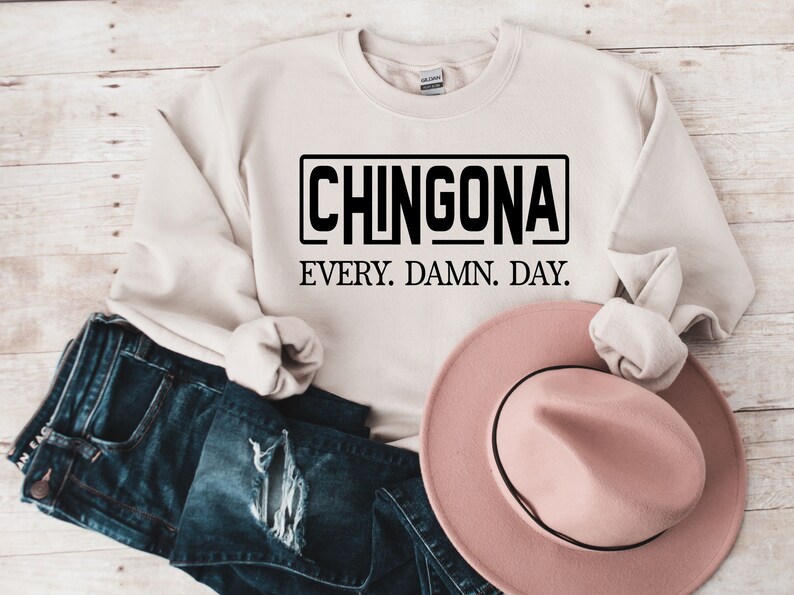 May include: A beige sweatshirt with the text "CHINGONA EVERY. DAMN. DAY." printed in black.