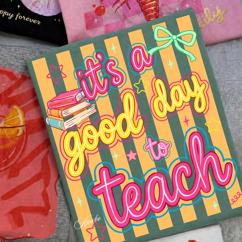 May include: A square, green and orange striped canvas with the text "It's a good day to teach" in bright colors. The design includes a stack of books, stars, and a bow. The artist's signature "Amelio" is at the bottom.