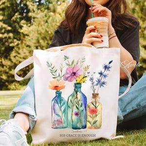 May include: White canvas tote bag with a floral design and the text "His Grace is Enough" and a scripture reference. The bag features three blue glass bottles with watercolour flowers.