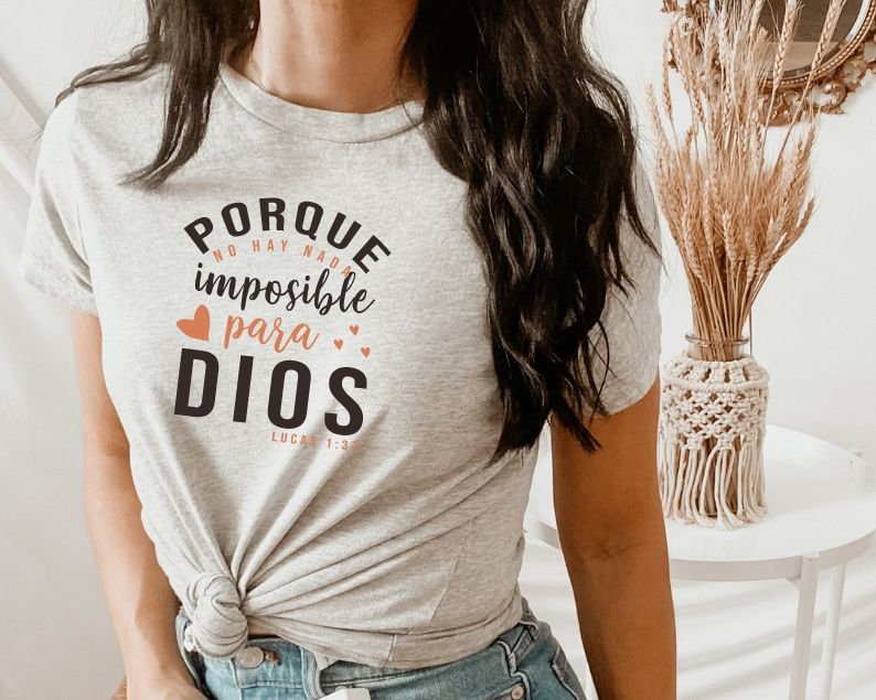 May include: Gray t-shirt with the text "PORQUE NO HAY NADA IMPOSIBLE PARA DIOS LUCAS 1:37" in black with a peach heart above the word "para" and two peach hearts to the right of the word "DIOS".
