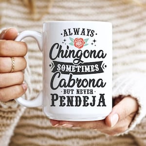 Puede incluir: Taza de cer&aacute;mica blanca con texto negro que dice "Always Chingona Sometimes Cabrona But Never Pendeja". Una rosa roja con hojas verdes est&aacute; por encima de la palabra "Chingona".