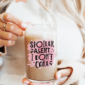 Pu&ograve; includere: Una tazza di vetro con uno sfondo acquerellato rosa e il testo "Spoiler Alert: I Don't Care" in lettere nere.
