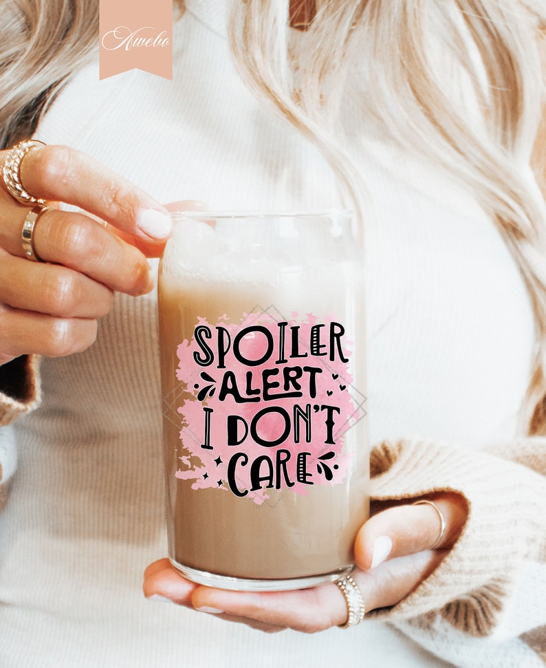 Pu&ograve; includere: Una tazza di vetro con uno sfondo acquerellato rosa e il testo "Spoiler Alert: I Don't Care" in lettere nere.