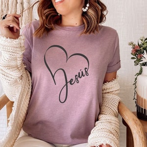 May include: A mauve t-shirt with a black heart design and the word "Jesus" inside the heart.