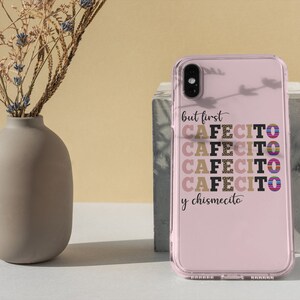 Puede incluir: Una funda de tel&eacute;fono rosa con la parte posterior transparente y un dise&ntilde;o en negro y dorado que dice "but first cafecito y chismecito".