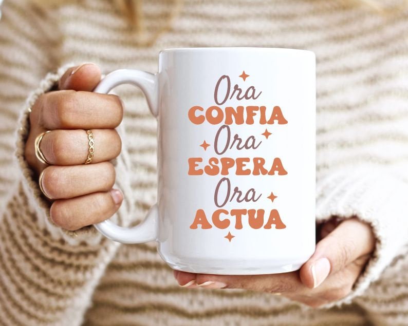 May include: White ceramic mug with the text "Ora Confia Ora Espera Ora Actua" in orange and brown lettering.