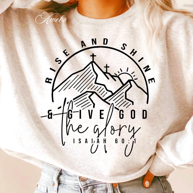 May include: White sweatshirt with a black graphic design featuring a mountain range with crosses on top, a sun, and the text "Rise and Shine & Give God the Glory, Isaiah 60:1".