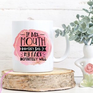Pu&ograve; includere: Tazza da caff&egrave; in ceramica bianca con un design ad acquerello rosa e il testo "Se la mia bocca non lo dice, il mio viso lo far&agrave; sicuramente".