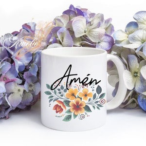 Puede incluir: Taza de cer&aacute;mica blanca con un dise&ntilde;o floral en tonos de amarillo, naranja y rojo. La palabra "Am&eacute;n" est&aacute; escrita en letras cursivas negras en la taza.