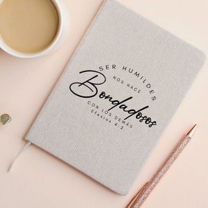 May include: A beige linen journal with the text "Ser humildes nos hace bondadosos con los dem&aacute;s Efesios 4:2" printed in black.