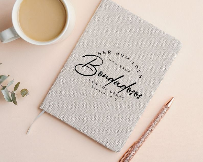 May include: A beige linen journal with the text "Ser humildes nos hace bondadosos con los dem&aacute;s Efesios 4:2" printed in black.