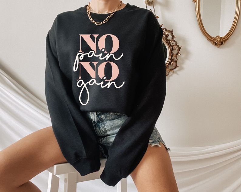 Pode incluir: Camisola de moletom preta com o texto "NO pain NO gain" em letras cor-de-rosa. A camisola &eacute; usada por uma pessoa com um colar de ouro.