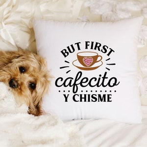 May include: White throw pillow with black text that reads "But first cafecito y chisme". A brown coffee cup with a pink heart design is pictured above the text.