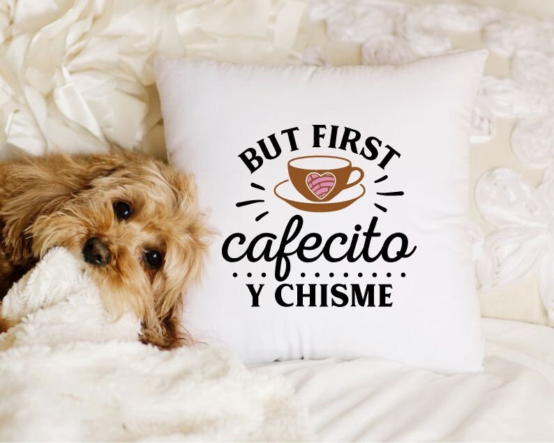 May include: White throw pillow with black text that reads "But first cafecito y chisme". A brown coffee cup with a pink heart design is pictured above the text.