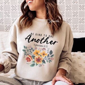 May include: Beige sweatshirt with a floral design and the text "Be Kind To One Another Ephesians 4:32".