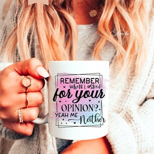 Pu&ograve; includere: Una tazza in ceramica bianca con uno sfondo acquerellato rosa e blu. La tazza presenta un testo nero che recita "Remember when I asked for your opinion? Yeah me Neither".