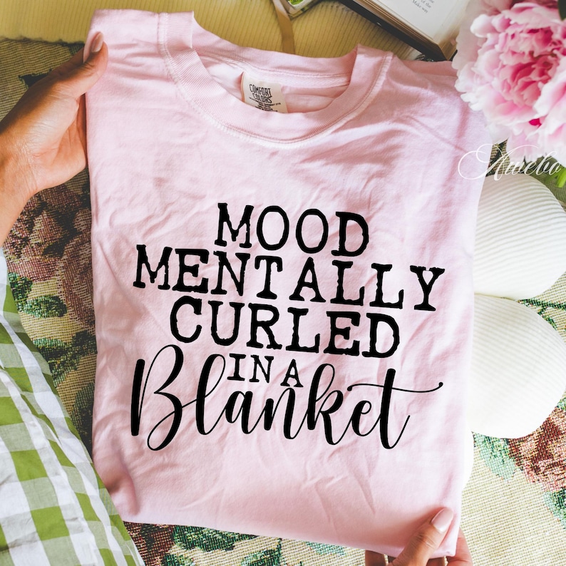 Puede incluir: Camiseta rosa con texto negro que dice "Mood Mentally Curled In A Blanket".