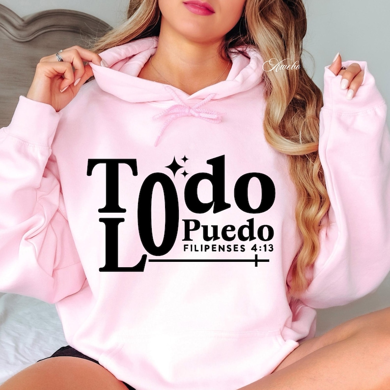 May include: A light pink hoodie with the words "Todo Puedo" in black, with the Bible verse "Filipenses 4:13" below. The hoodie has a drawstring and a hood.