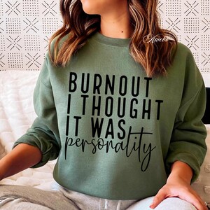 Puede incluir: Una sudadera verde con el texto "Burnout I thought it was personality" impreso en negro.