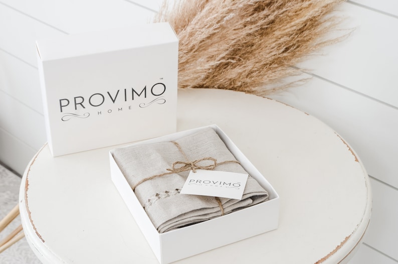 May include: A white box with the text "PROVIMO HOME" on it. The box is open and contains a folded linen towel with a brown twine bow and a small white tag that says "PROVIMO HOME".
