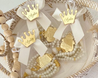 May include: Three white pearl prayer beads with gold accents and a gold charm with Arabic script. Each bead set is packaged in a clear plastic bag with a gold crown and the name "Azalea" on a mirror-like tag.