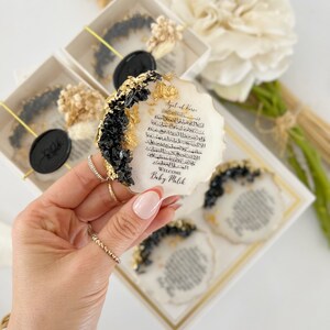 May include: A white oval resin plaque with black and gold accents. The plaque features Arabic calligraphy and the text "Ayatul Kursi" and "Welcome Baby Malik".