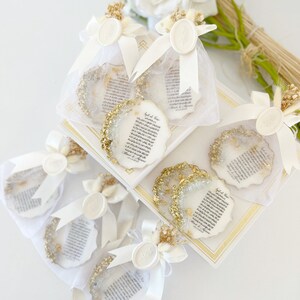 May include: White organza bags with gold glitter and white wax seals, filled with small white paper scrolls with gold lettering. The scrolls have Arabic text and the words "Special Love" written on them. The bags are tied with white ribbon and decorated with dried flowers.