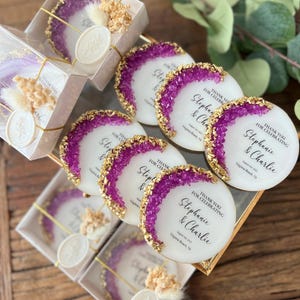 May include: Purple and gold wedding favor coasters with the text "Thank you for celebrating Stephanie & Charlie August 1st, 2023 Virginia Beach, VA"