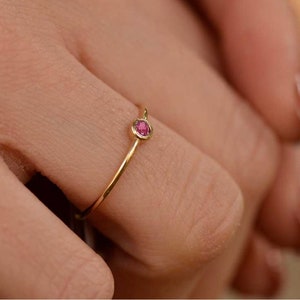 Può includere: Un delicato anello d'oro con una piccola pietra preziosa rosa rotonda.