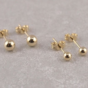 May include: Three pairs of gold ball stud earrings. Each earring features a small, round gold ball.