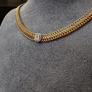 May include: A gold chain necklace with a square-shaped diamond pendant.