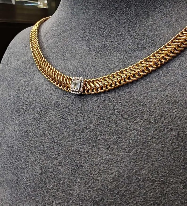 May include: A gold chain necklace with a square-shaped diamond pendant.