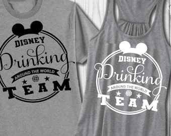 Puede incluir: Una camiseta gris y un top sin mangas gris con un diseño gráfico en blanco y negro que dice "Disney Drinking Around the World Team".