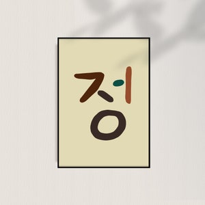Puede incluir: Un cuadro enmarcado con caracteres coreanos en marrón, naranja y verde sobre un fondo crema. El diseño minimalista está enmarcado en negro, ideal para la decoración del hogar o la oficina.
